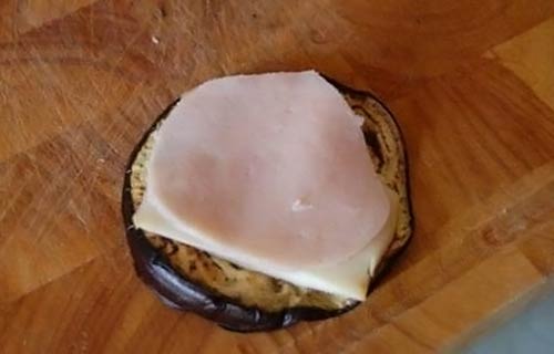 Положите на баклажана копчены сыр и ветчину