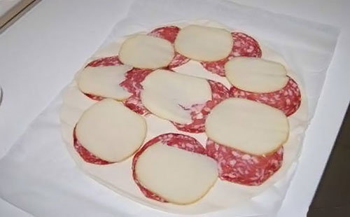 На тесто положите слой колбасы и слой сыра